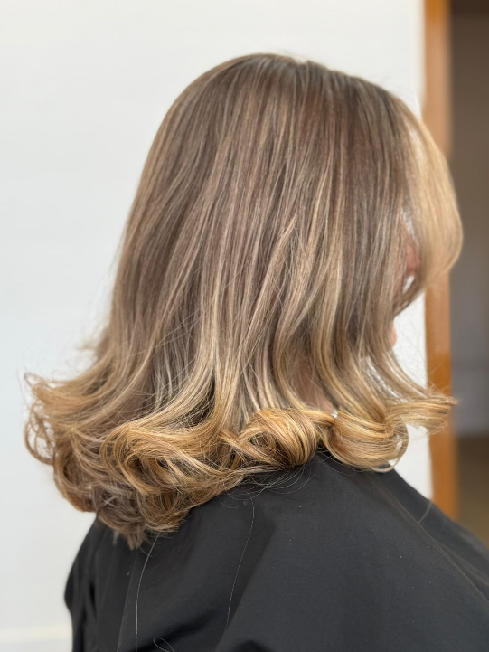 Blondes Haar mit glatten Ansätzen und voluminösen Locken an den Spitzen